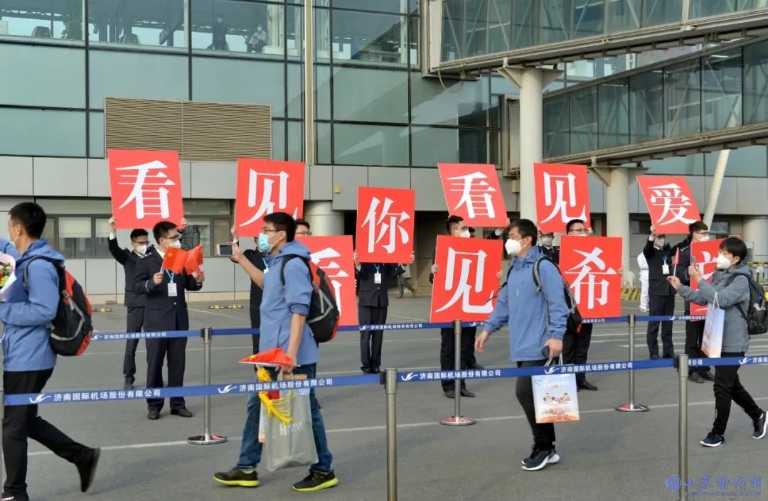 《停机坪上,“抗疫英雄,欢迎回家”等横幅格外醒目,山东省援助湖北医疗队队旗迎风飘扬。医疗队员们面带笑容,在停机坪上列队集结,大家脸上洋溢着胜利的喜悦》 摄影:王琦.jpg
